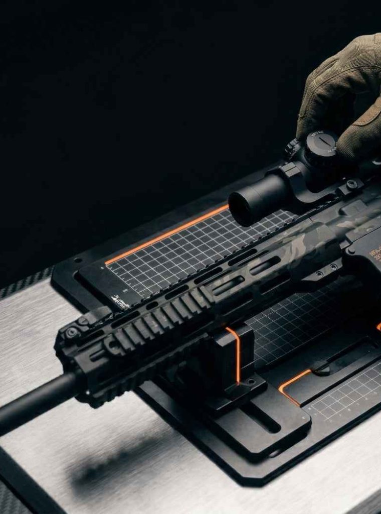 A gunsmith adjusting the optic on a finished custom AR-15 rifle.